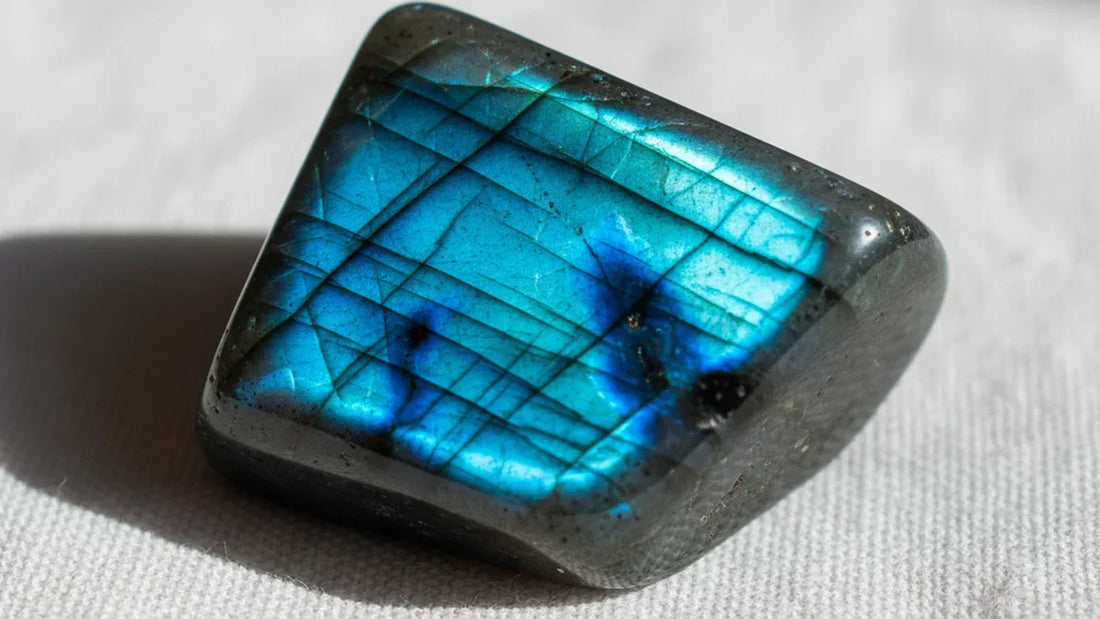 Primer plano de labradorita pulida mostrando la espectacular labradorescencia azul y verde, efecto óptico de interferencia de luz en base gris oscuro