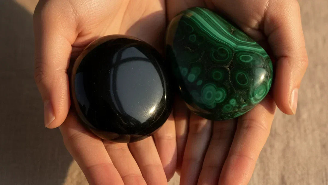 Piedra de escorpio: obsidiana negra y malaquita verde sostenidas entre manos con luz natural - Anna Piedra