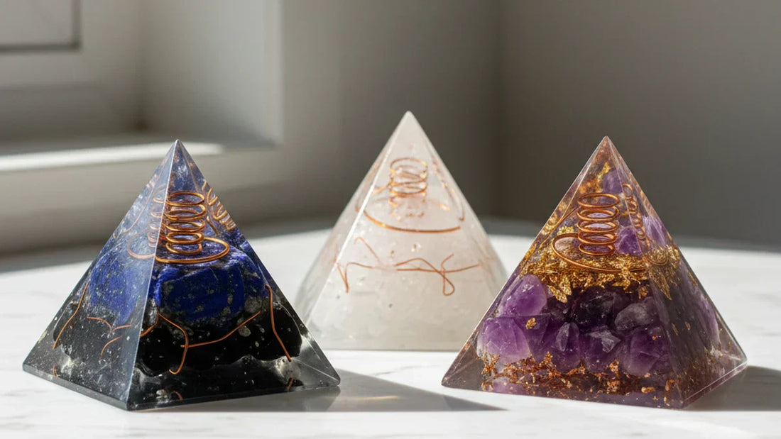 Tres pirámides de orgonita con piedras naturales lapislázuli obsidiana cuarzo blanco y amatista sobre mármol blanco con luz natural