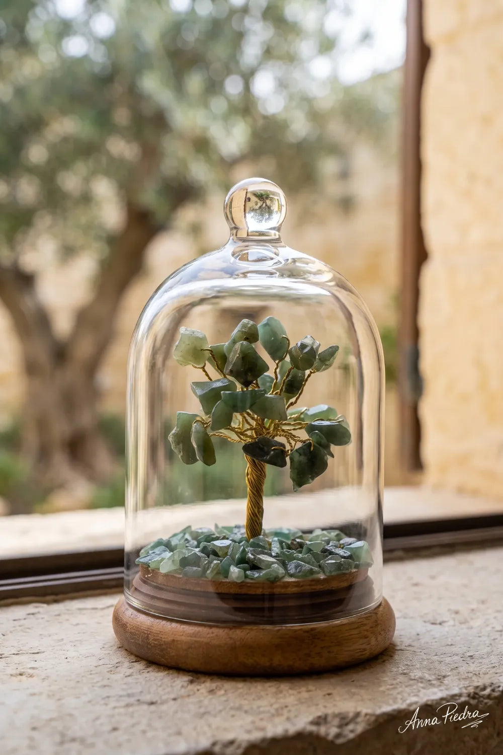 Árbol de la Vida de Aventurina verde bajo campana de cristal con base de madera, junto a una ventana con vistas al jardín – Anna Piedra
 Copier