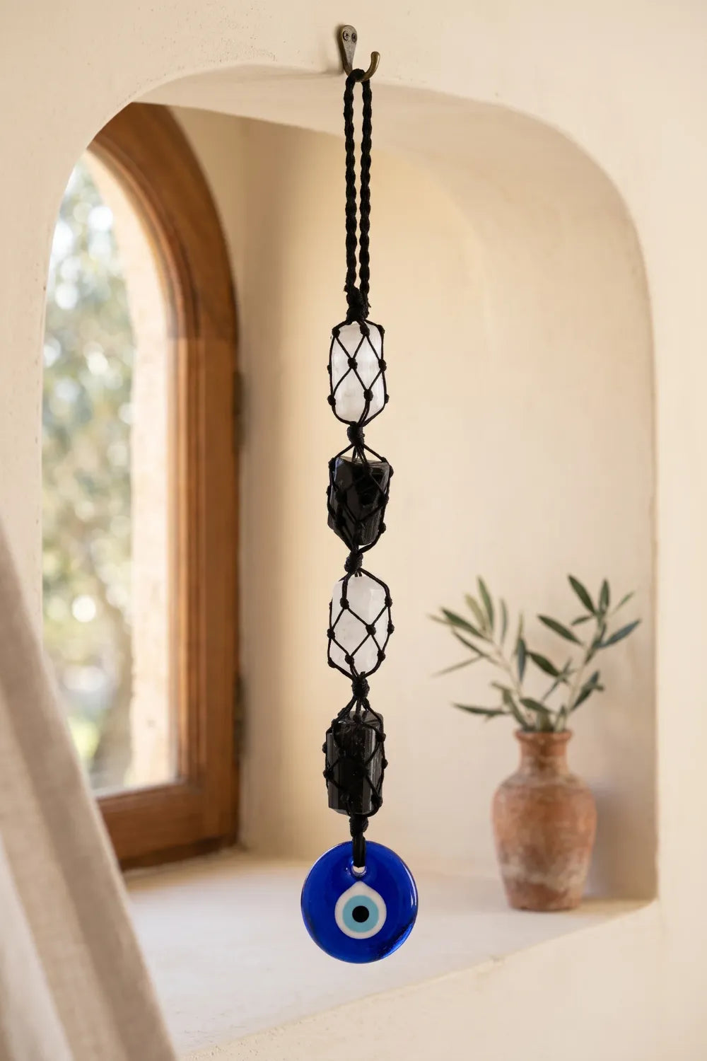 Amuleto colgante con dos piedras de turmalina negra, dos piedras blancas de selenita y ojo turco azul, tejido con cordón negro.