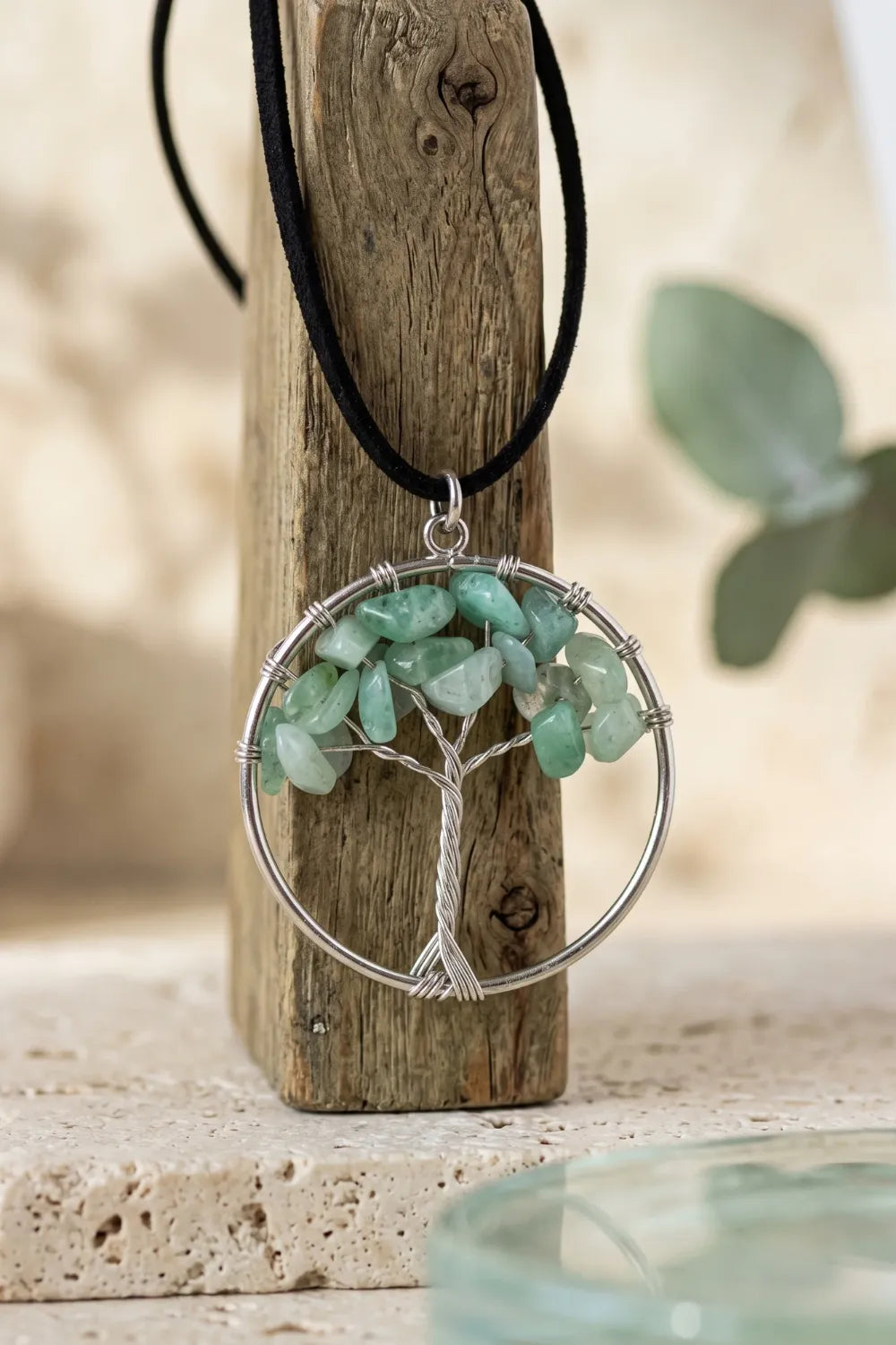 Primer plano del colgante Árbol de la Vida de jade colgado sobre una pieza de madera rústica.