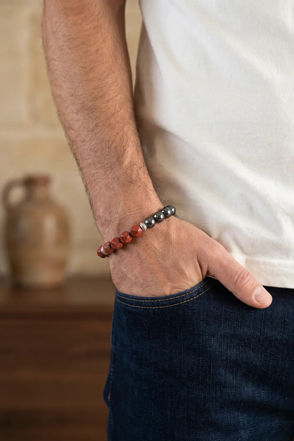 Hombre llevando una pulsera de jaspe rojo y hematita magnética en la muñeca.