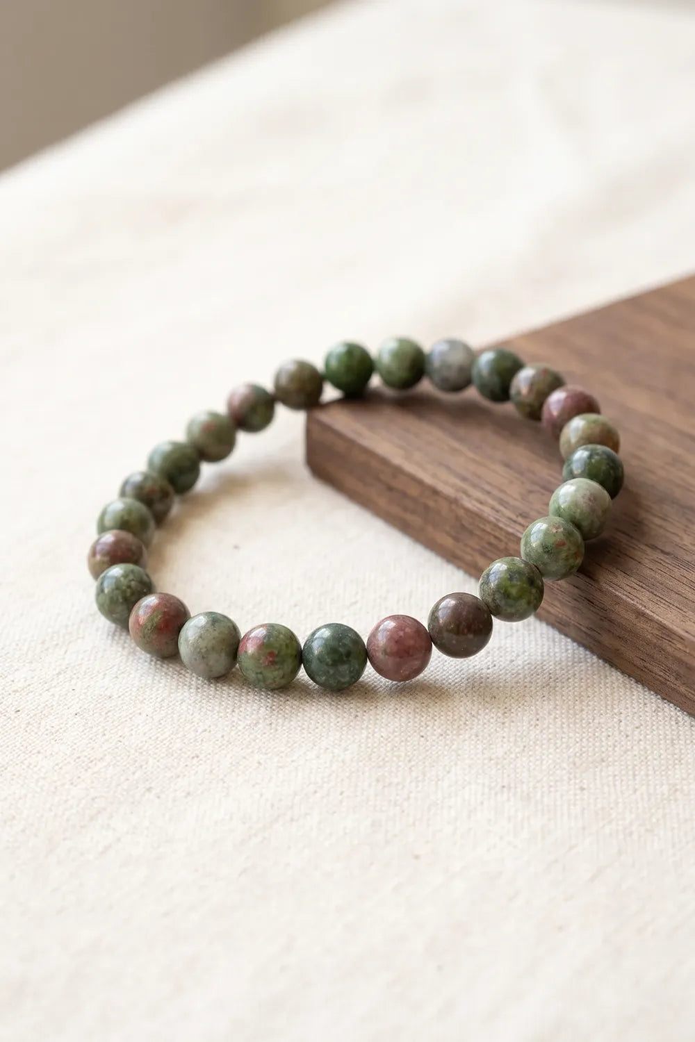 Detalle de una pulsera de jaspe verde con cuentas pulidas en tonos verdes y rosados.