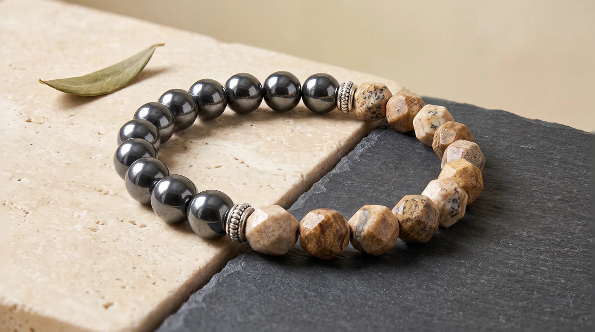 Pulsera de jaspe paisaje y hematita magnética colocada sobre una superficie de piedra y pizarra.