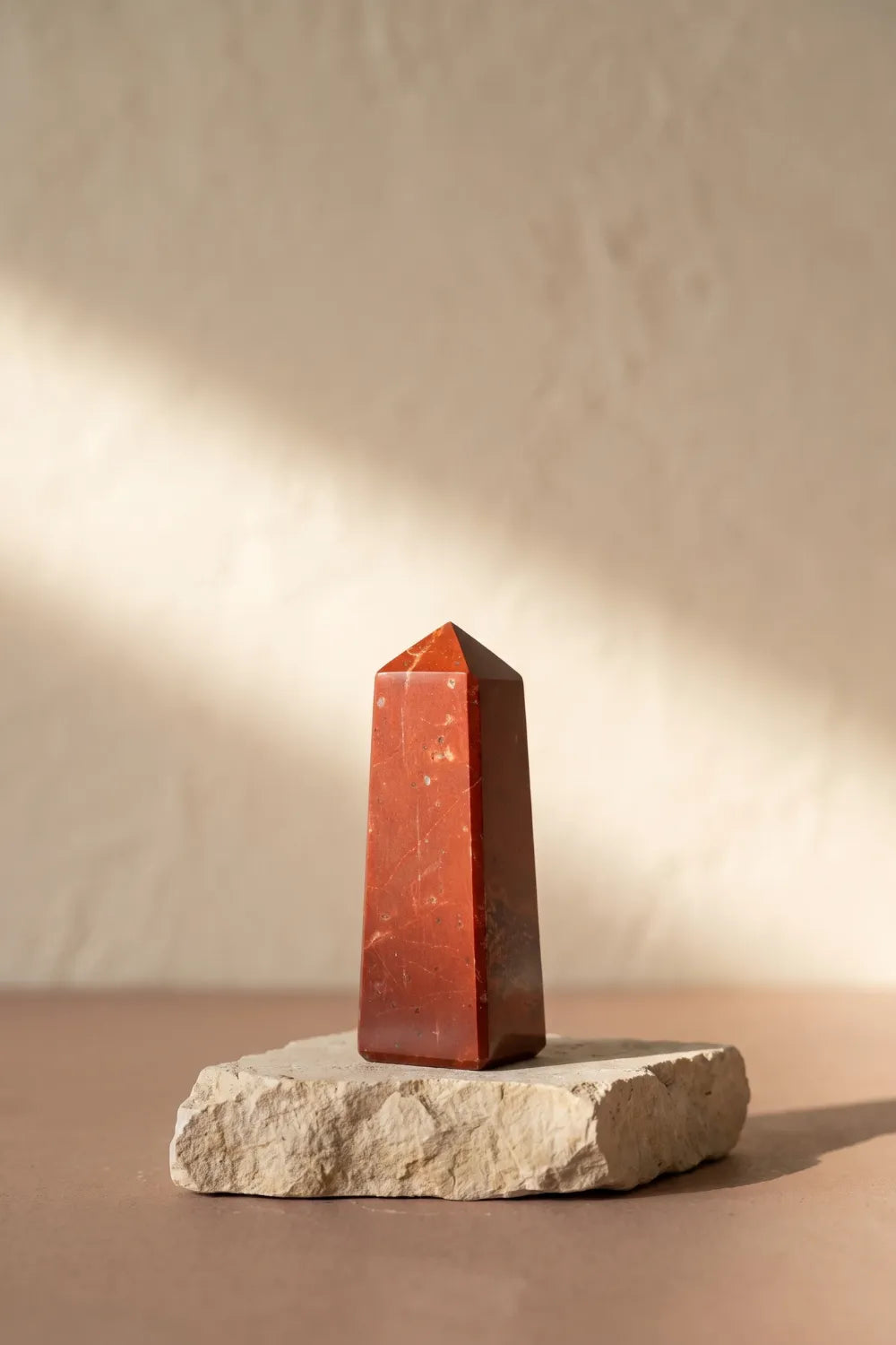 Punta de jaspe rojo pulida de Anna Piedra sobre base de piedra clara.