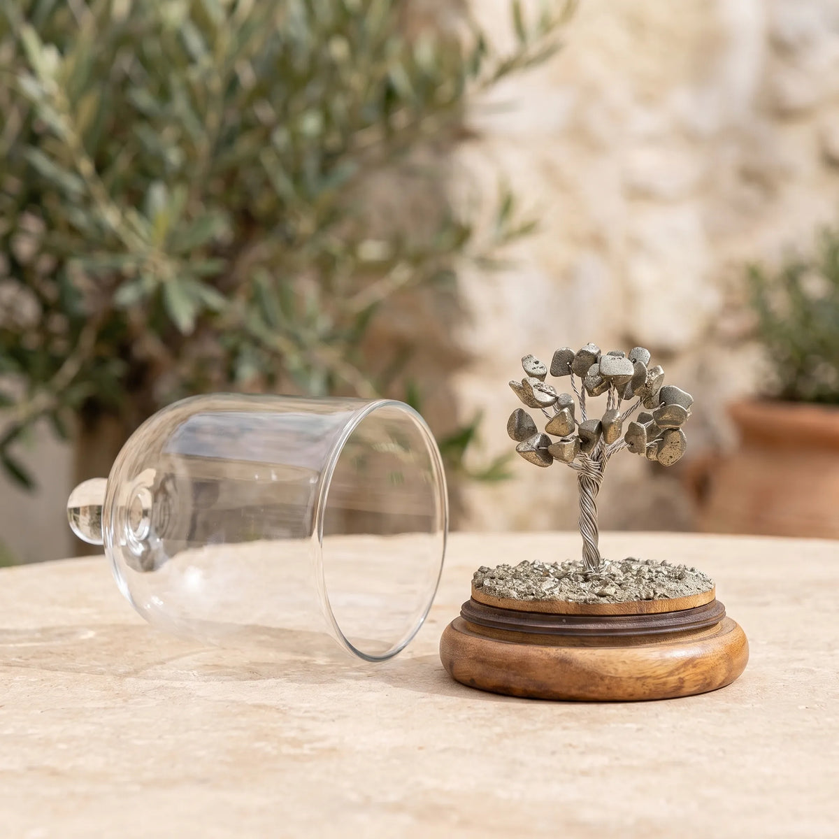 Árbol de la vida de pirita natural con la cúpula de cristal abierta sobre una superficie de piedra. anna piedra