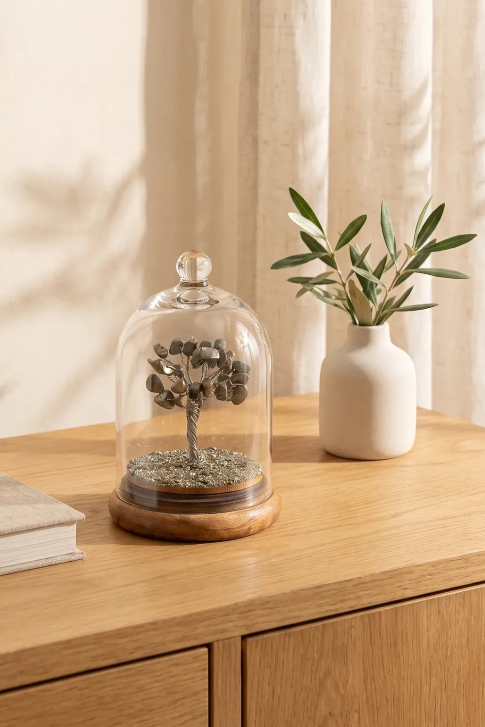 Árbol de la vida de pirita natural bajo cúpula de cristal sobre un mueble de madera. anna piedra