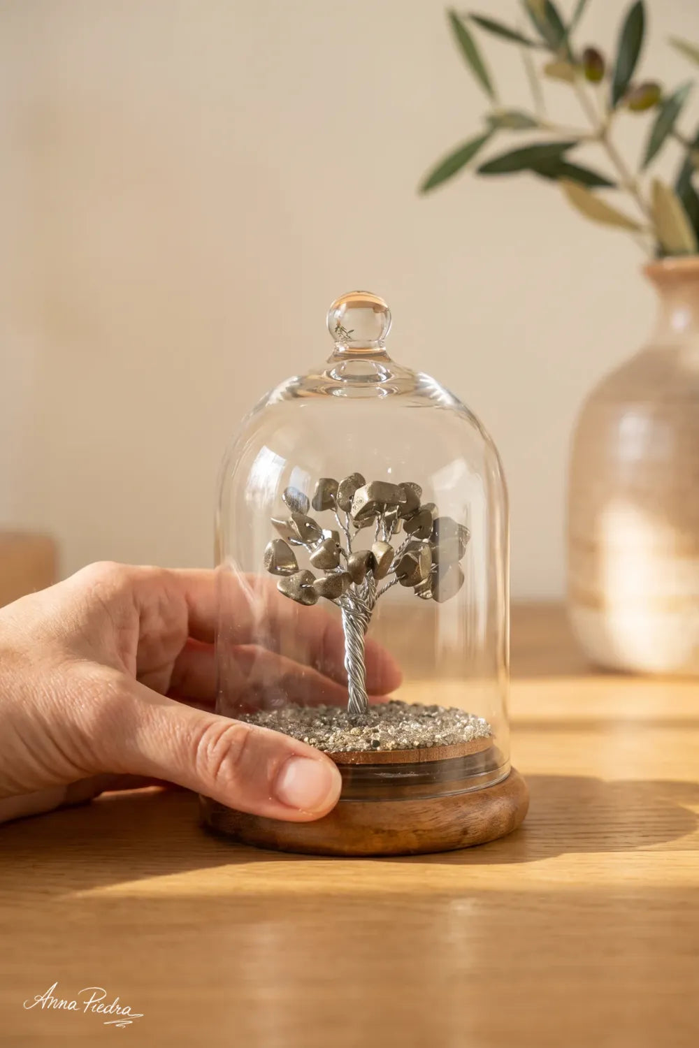 Árbol de la vida de pirita bajo cúpula de cristal sostenido con la mano. anna piedra