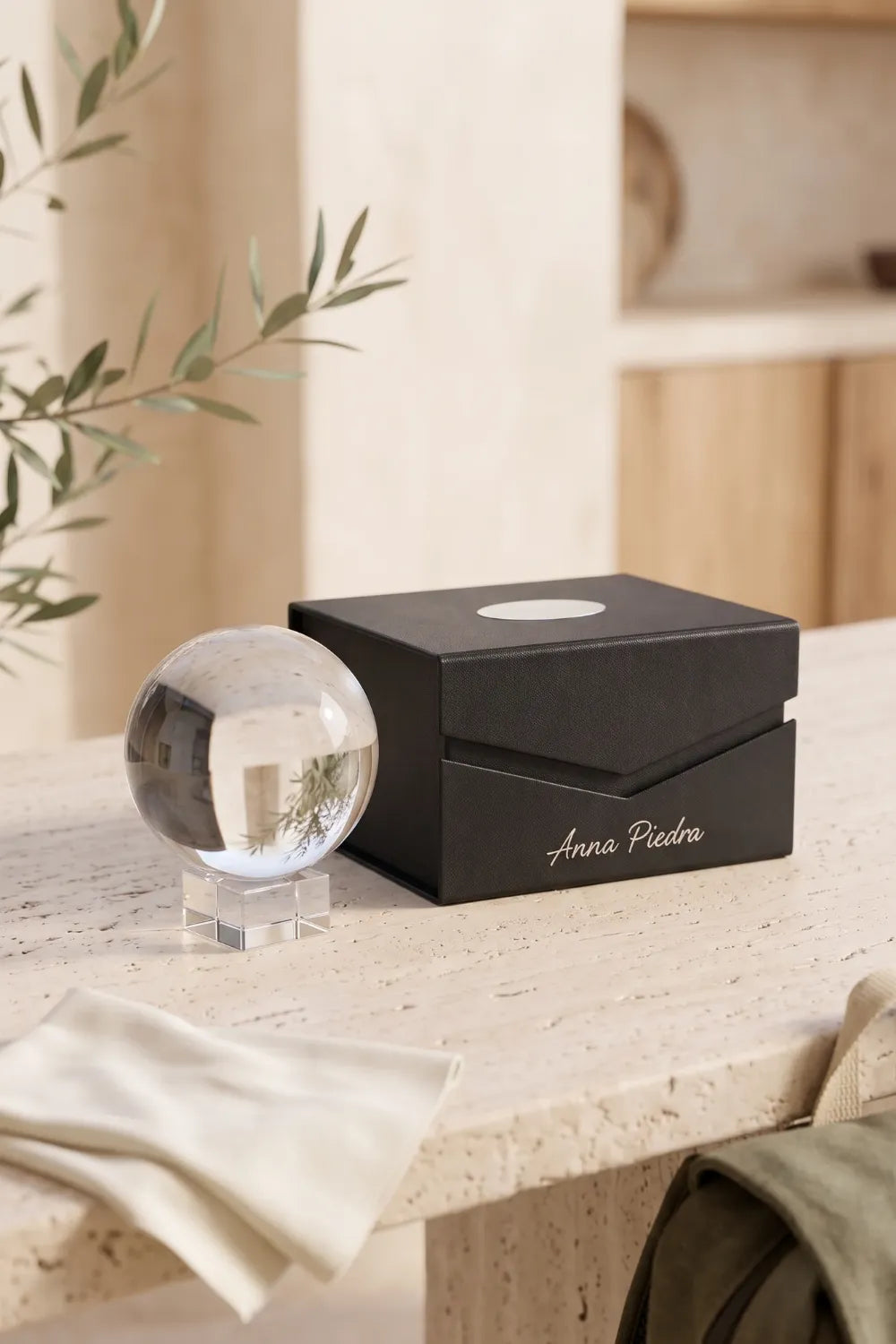 Bola de cristal para fotografía con soporte transparente y caja negra Anna Piedra sobre una superficie de piedra natural.