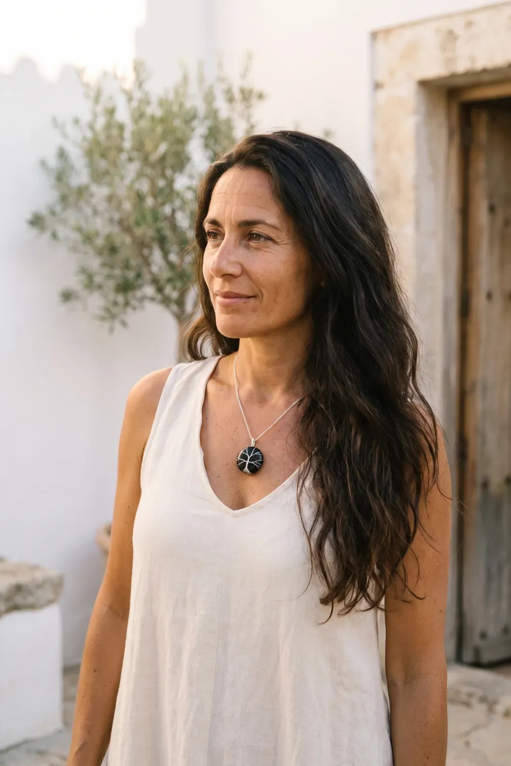Mujer llevando un collar árbol de la vida de ónix negro en un exterior mediterráneo. anna piedra