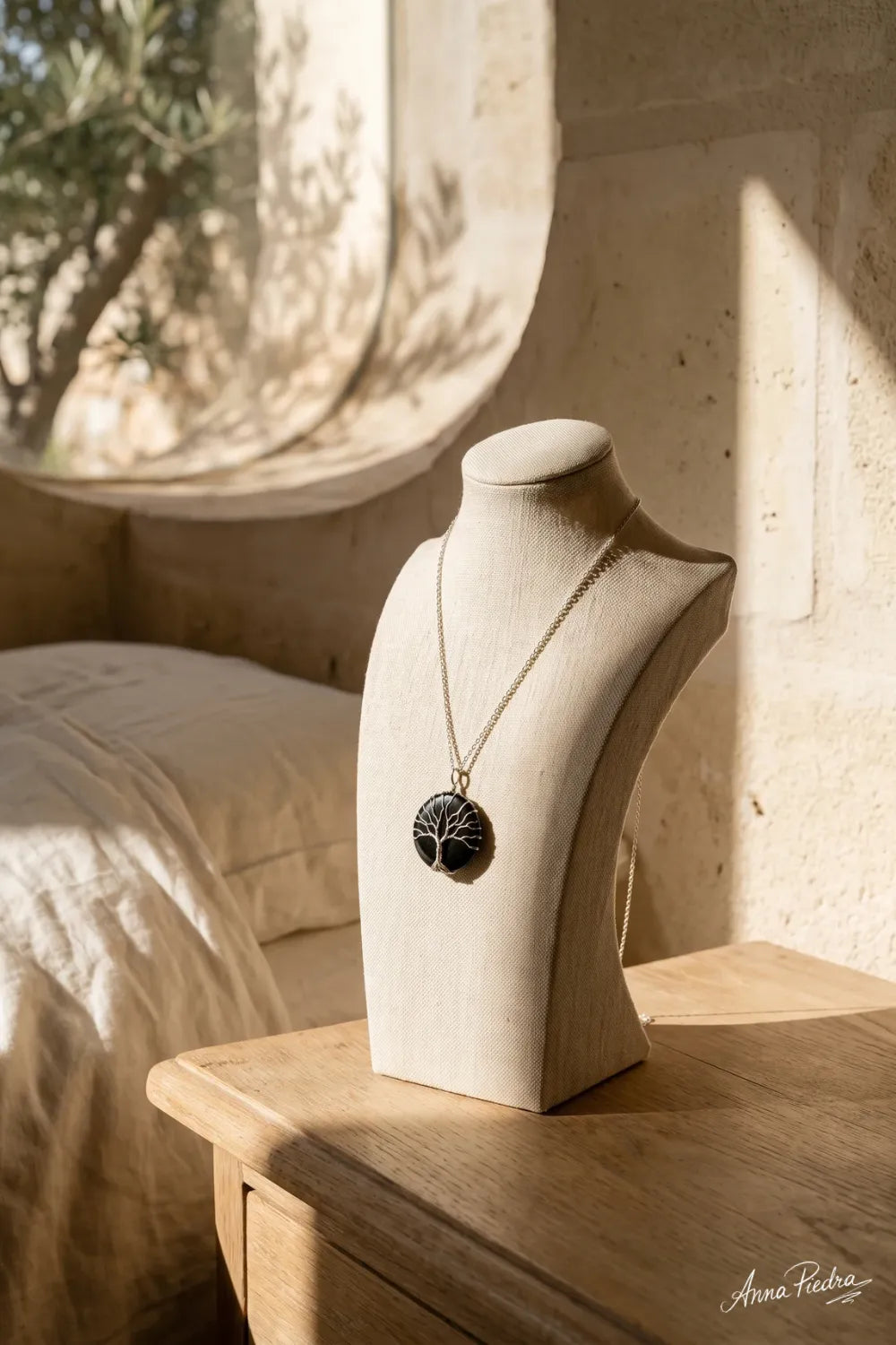 Collar árbol de la vida de ónix negro presentado sobre un expositor de tela en un interior luminoso. anna piedra