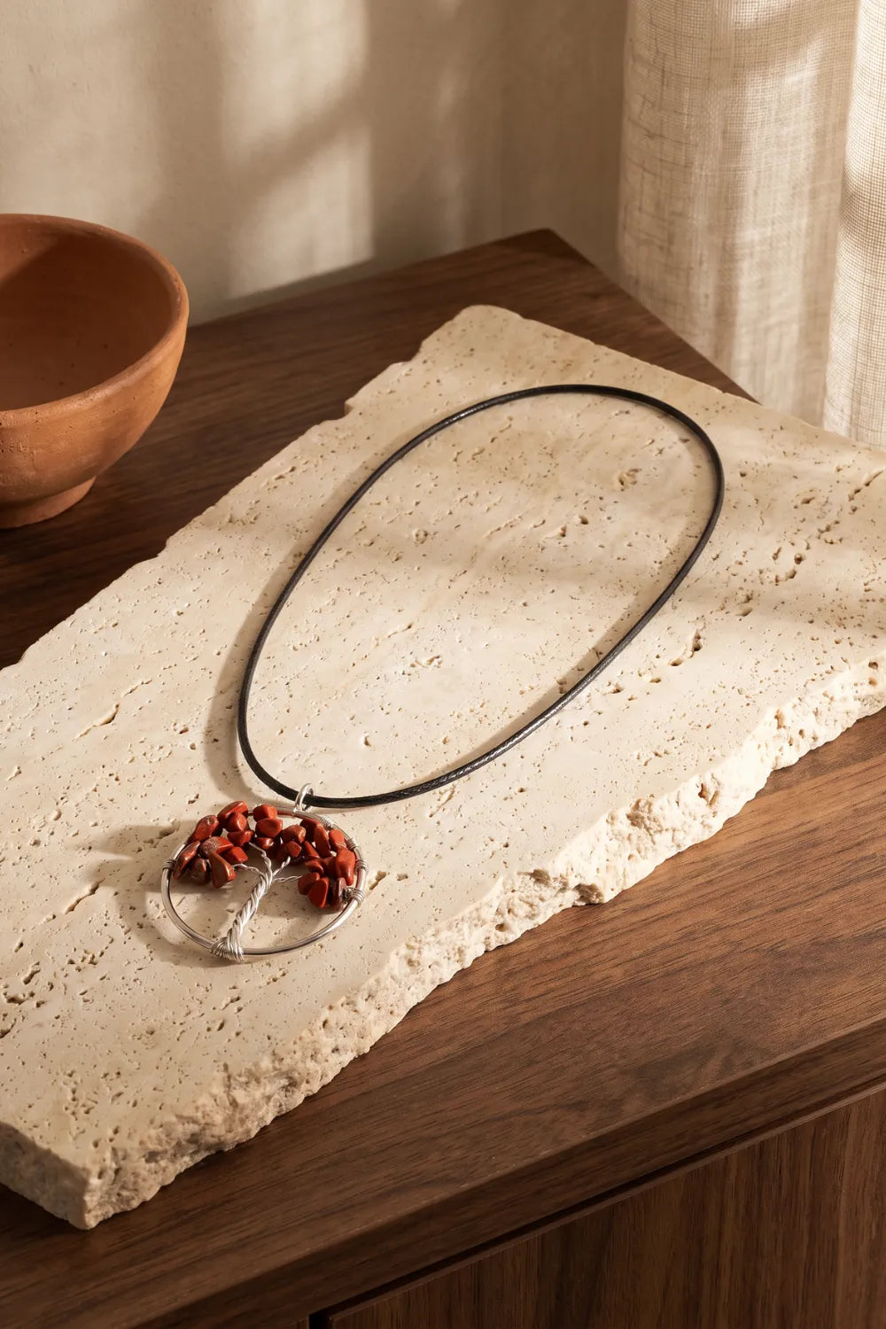 Collar de jaspe rojo natural con colgante circular Árbol de la Vida de alambre plateado y cordón negro, sobre piedra travertino y madera – Anna Piedra