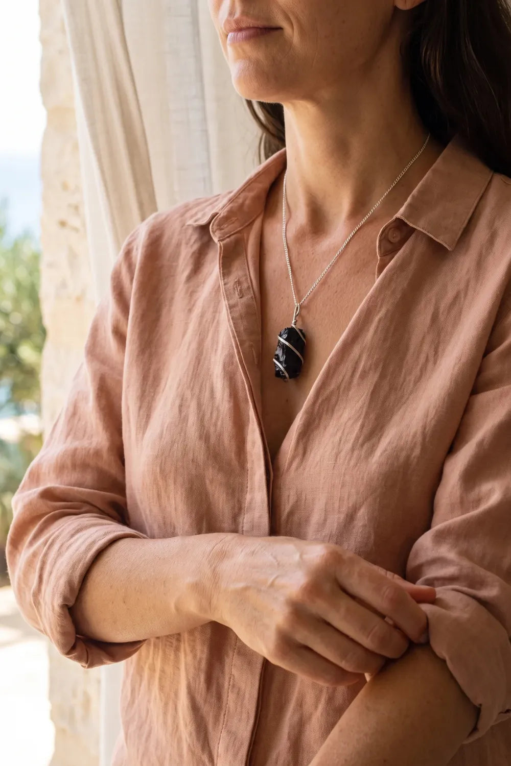 Detalle de una mujer llevando un collar de ónix negro en bruto con cadena plateada. anna piedra