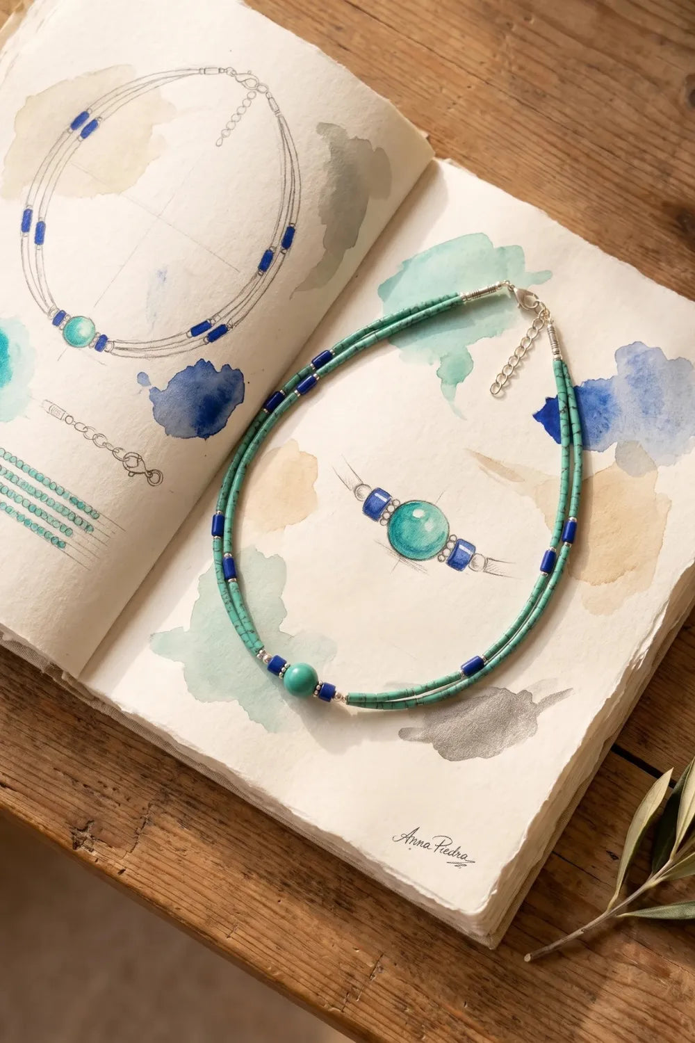 Collar de lapislázuli y malaquita sobre un cuaderno de bocetos firmado por Anna Piedra