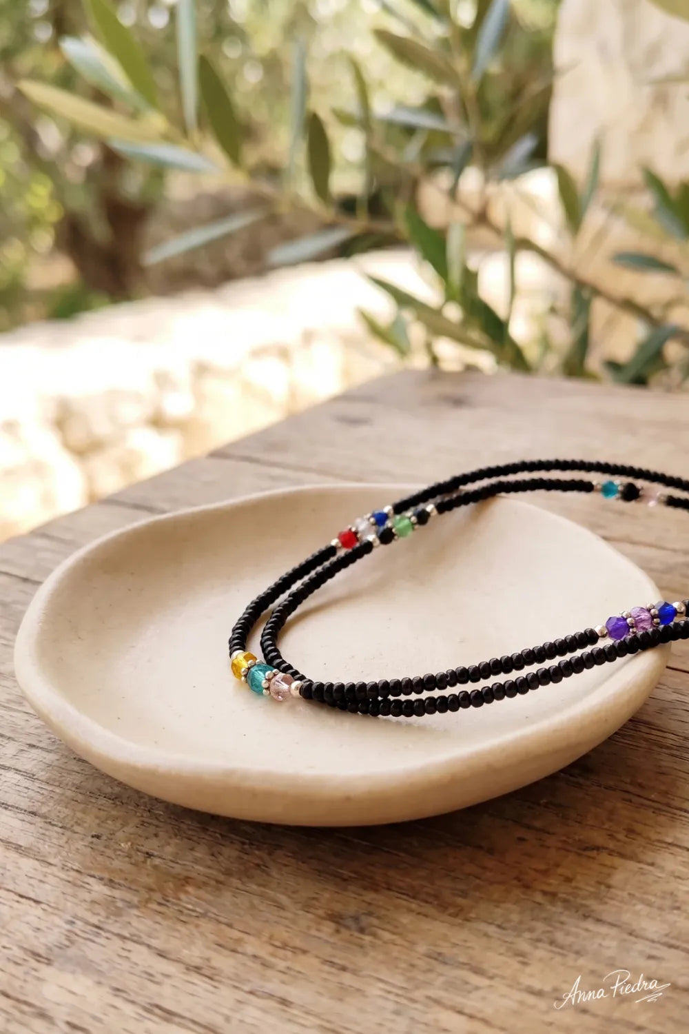 Detalle de un collar nepalí de ónix de doble hilera sobre un plato de cerámica clara. anna piedra