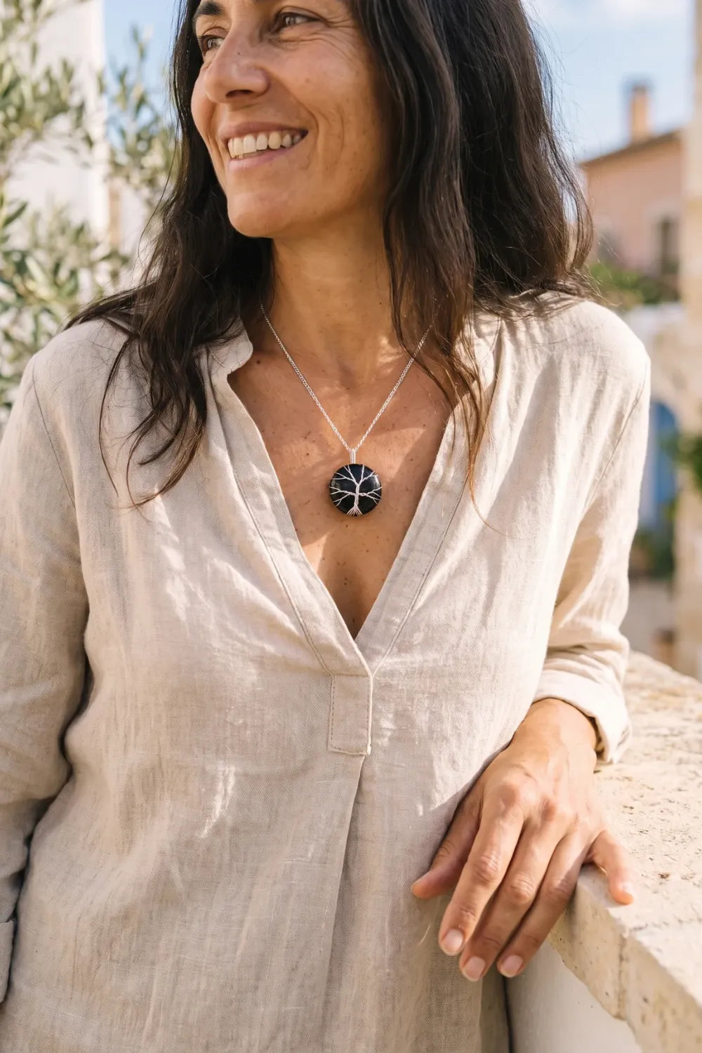 Primer plano de una mujer con collar árbol de la vida de ónix negro y cadena plateada. anna piedra