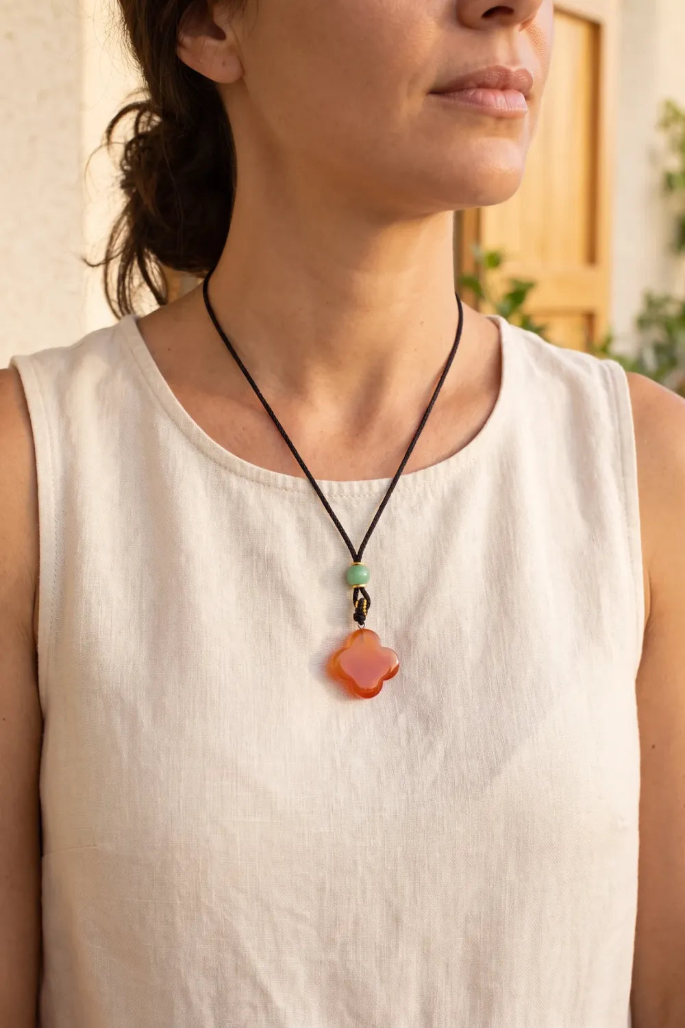 Mujer llevando un collar con trébol de jade rojo y perla de jade verde