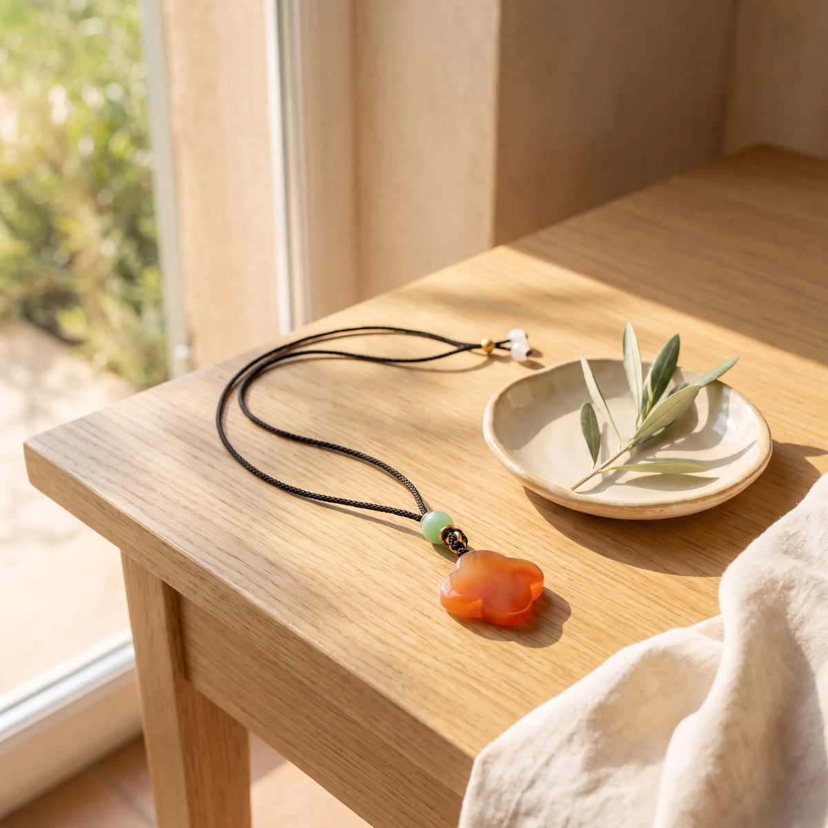 Collar con trébol de jade rojo y perla de jade verde sobre una mesa de madera
