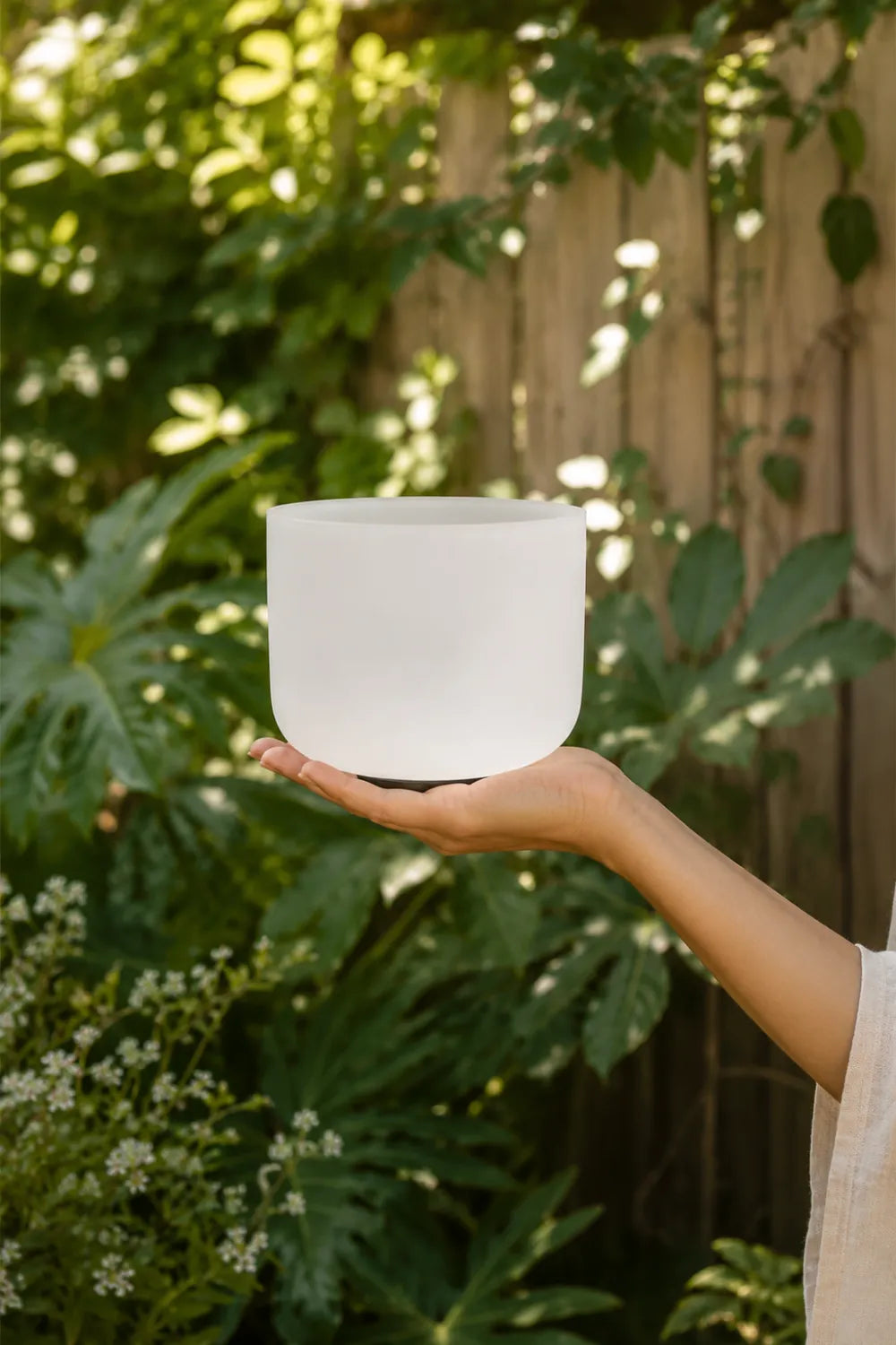 Mujer sosteniendo un cuenco de cuarzo blanco esmerilado entre sus manos en un jardín natural - Anna Piedra