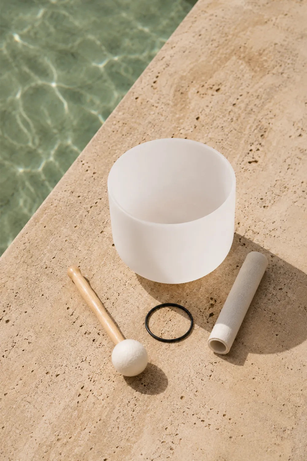 Cuenco de cuarzo blanco esmerilado con sus dos mazos y anillo de base negro sobre superficie de piedra natural - Anna Piedra