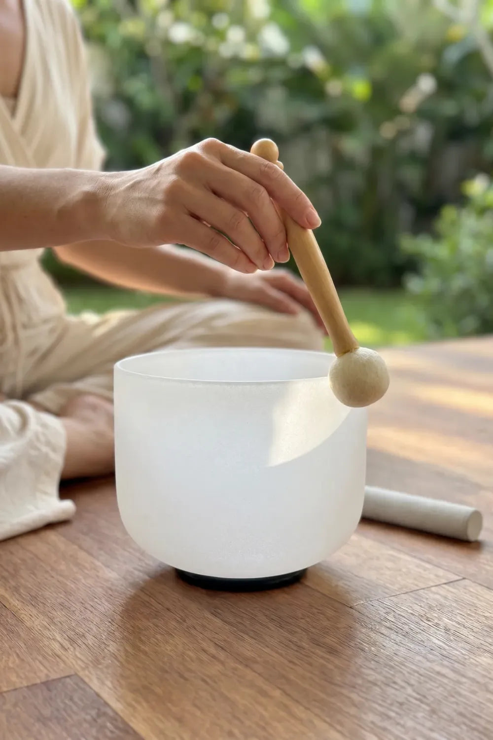 Mujer tocando un cuenco de cuarzo con mazo de piel de oveja para meditación y bienestar - Anna Piedra
