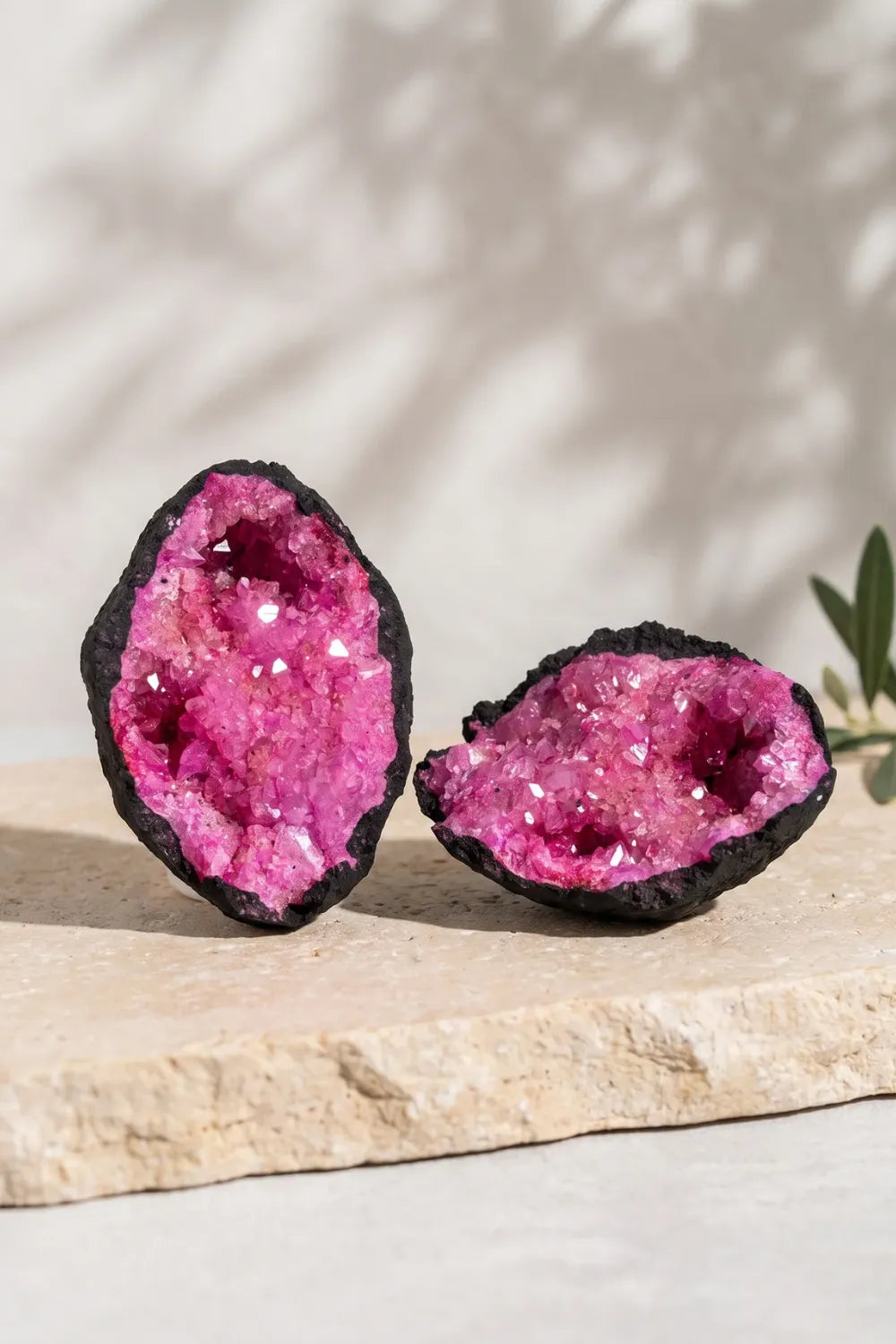 Geoda de calcita rosa abierta en dos mitades mostrando sus cristales rosas sobre una superficie de piedra clara.