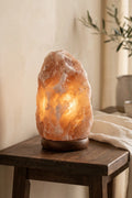 Lámpara de sal natural del Himalaya encendida sobre una mesa de madera
