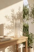 Lámpara de selenita con símbolos chakras sobre mesa madera plantas luz natural - Anna Piedra
