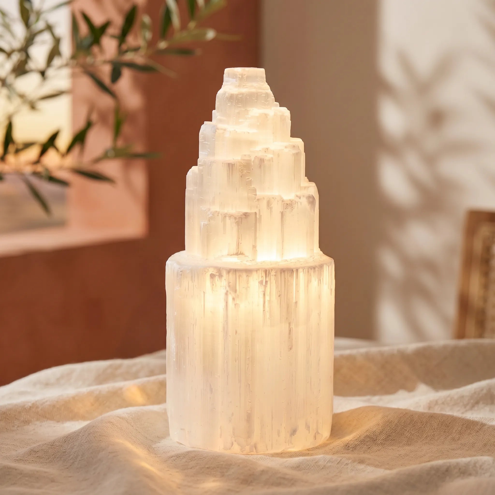 Lámpara de selenita encendida sobre tela beige luz cálida decoración - Anna Piedra