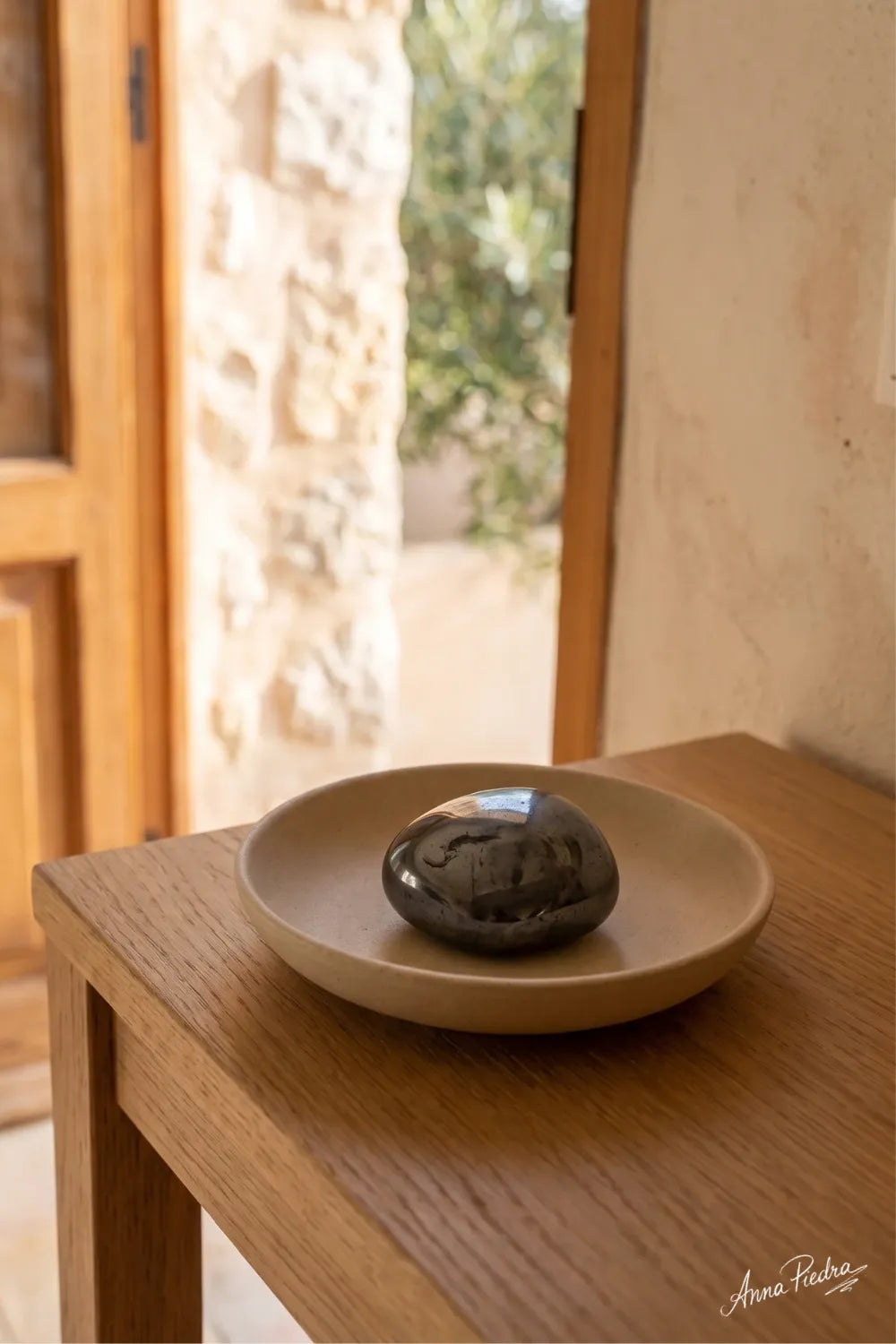 Piedra de hematita pulida colocada sobre una bandeja en un mueble junto a la entrada de casa. anna piedra