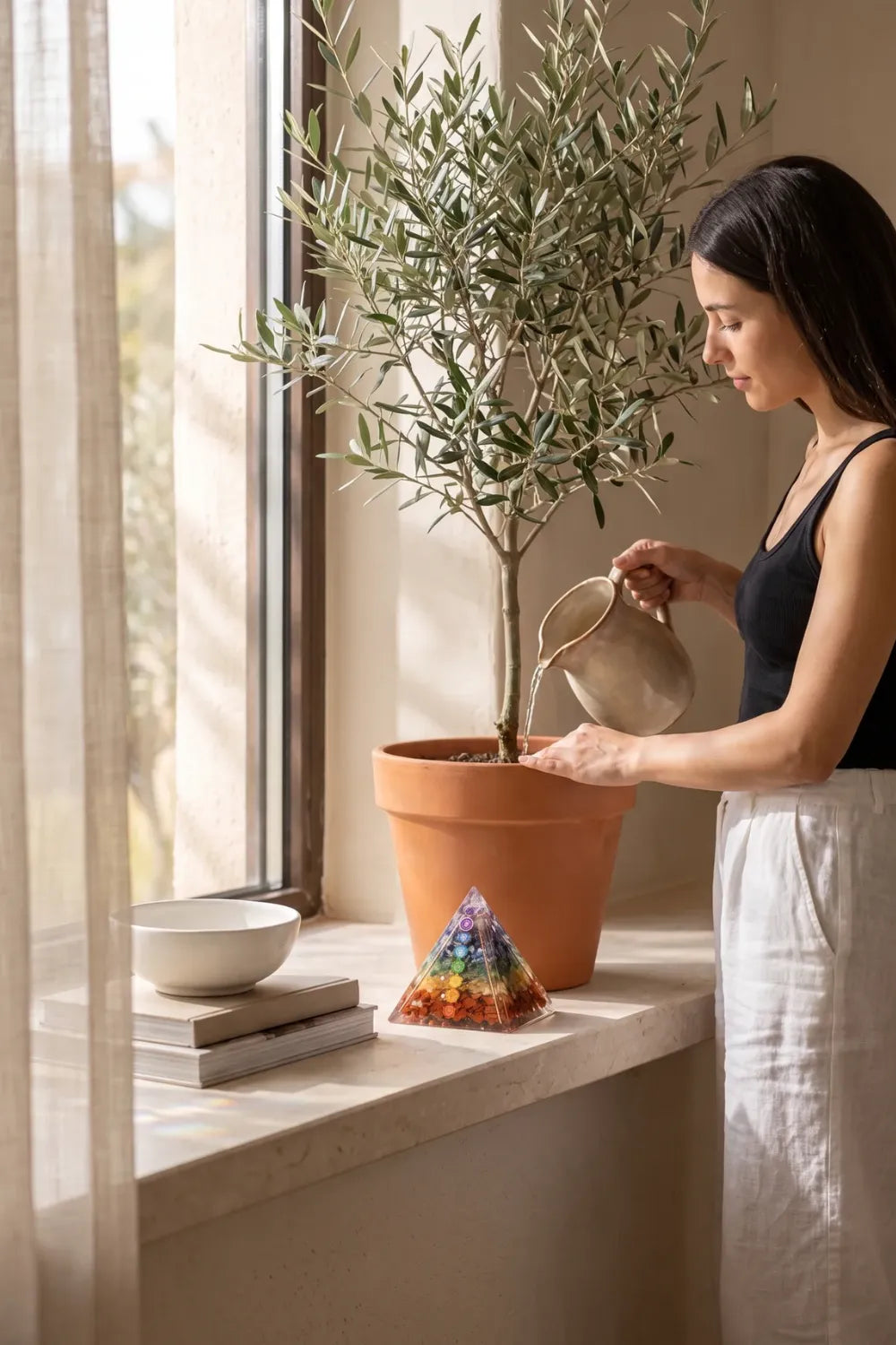 Pirámide de orgonita 7 chakras junto a un olivo en un interior luminoso anna piedra