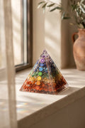 Pirámide de orgonita 7 chakras en primer plano sobre una superficie clara junto a una ventana. anna piedra