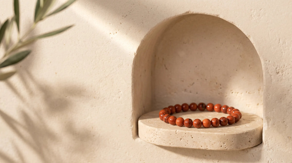 Pulsera de cornalina con cuentas redondas pulidas en tonos naranjas y rojizos, colocada sobre una repisa de piedra natural en un nicho decorativo – Anna Piedra