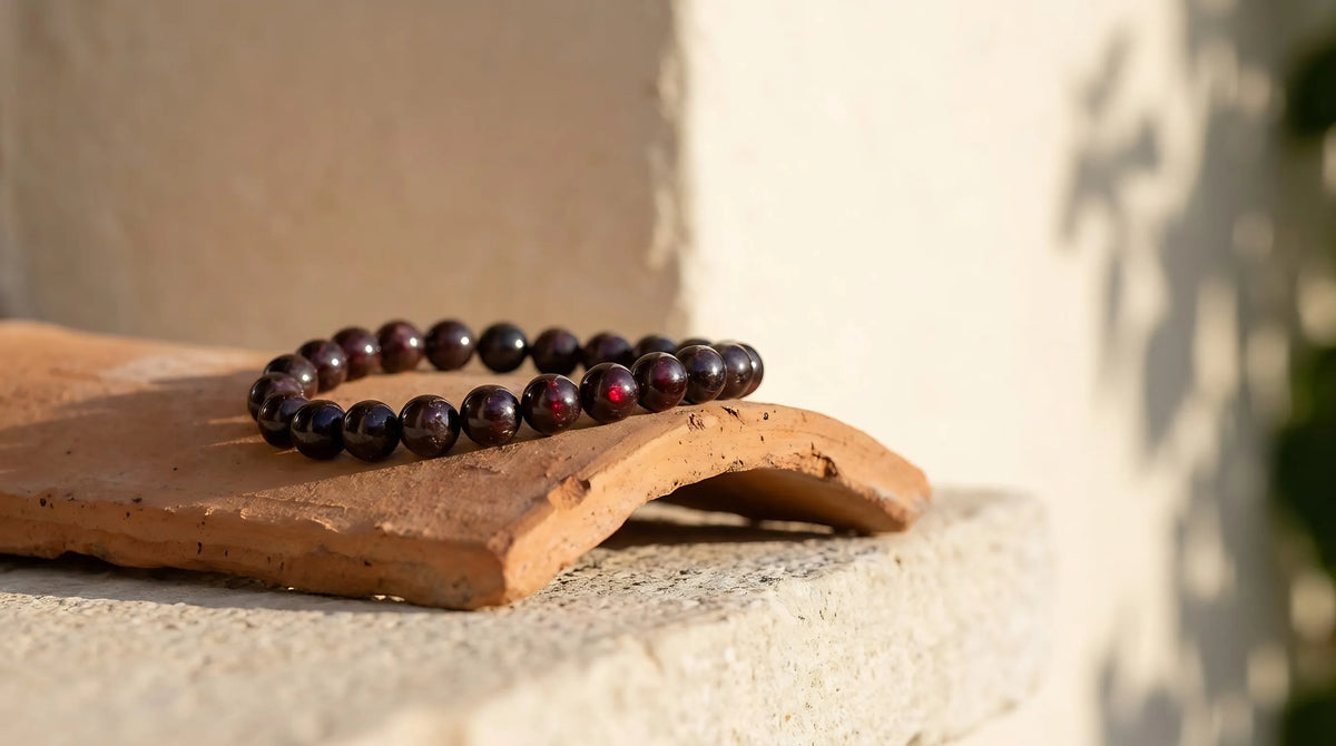 Pulsera de granate natural de cuentas redondas rojo granate colocada sobre una teja de barro con luz cálida