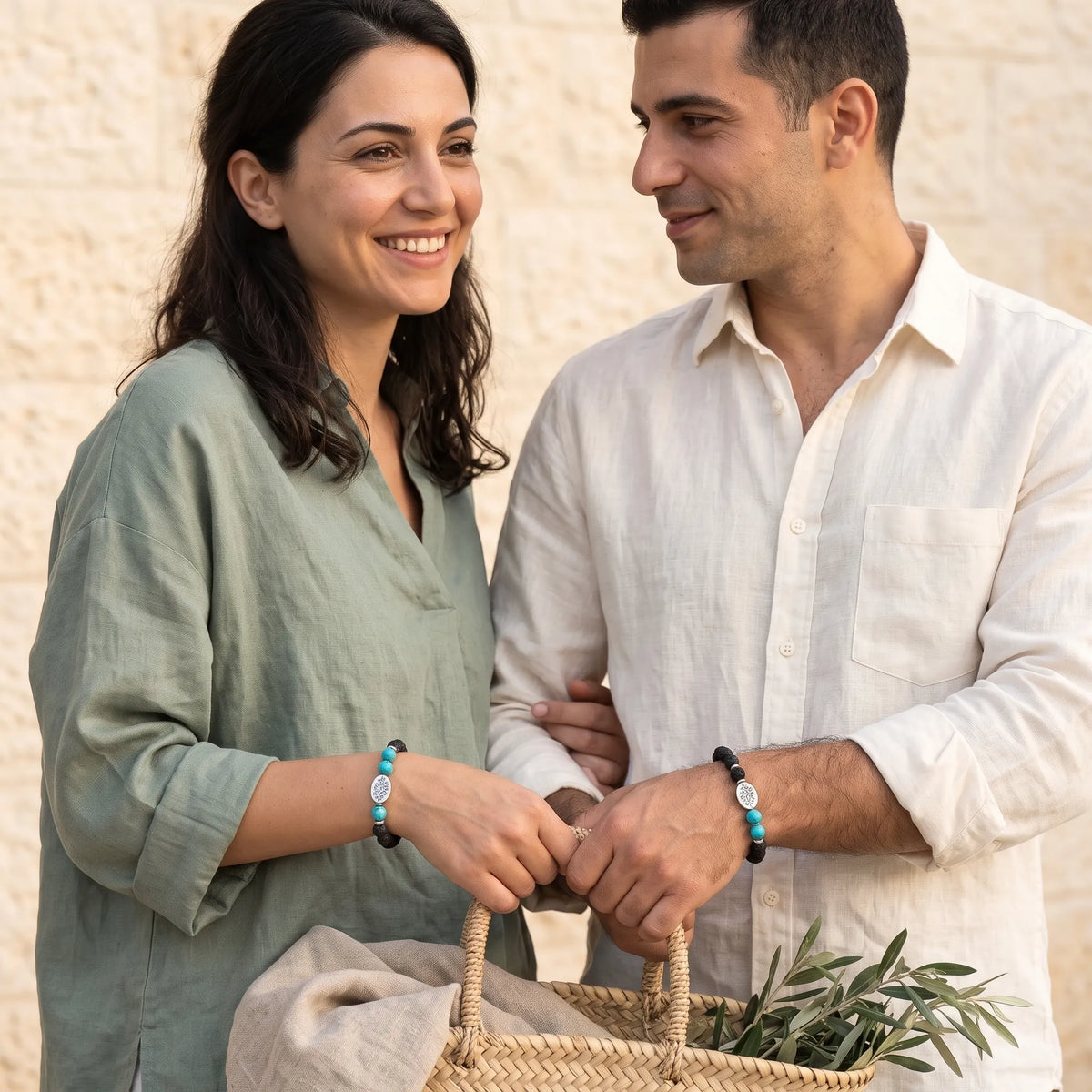Pareja sonriendo al aire libre luciendo una pulsera de lava y turquesa con detalles plateados.