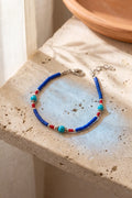 Pulsera nepalí de ónix azul colocada sobre una superficie de piedra clara junto a una cortina y una fuente de barro anna piedra