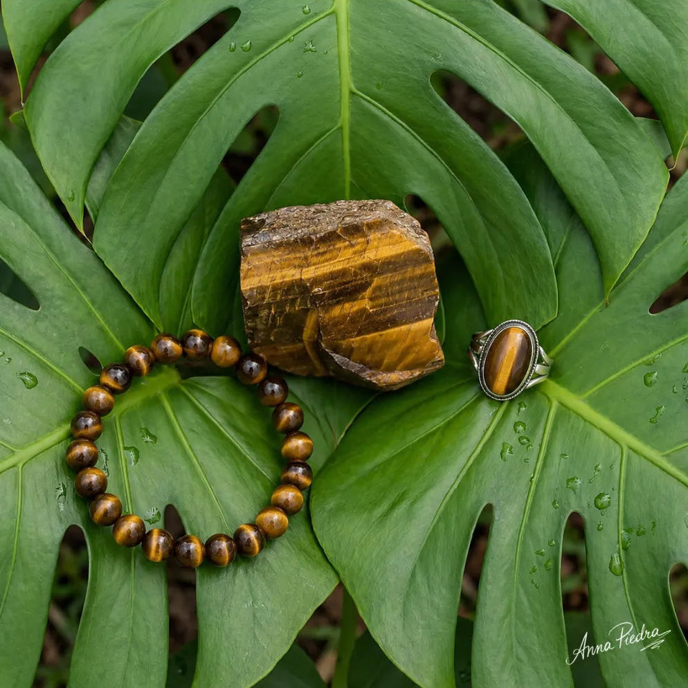 Pierre oeil du tigre brute avec bracelet et bague en pierre naturelle sur feuilles tropicales vertes | Anna Piedra